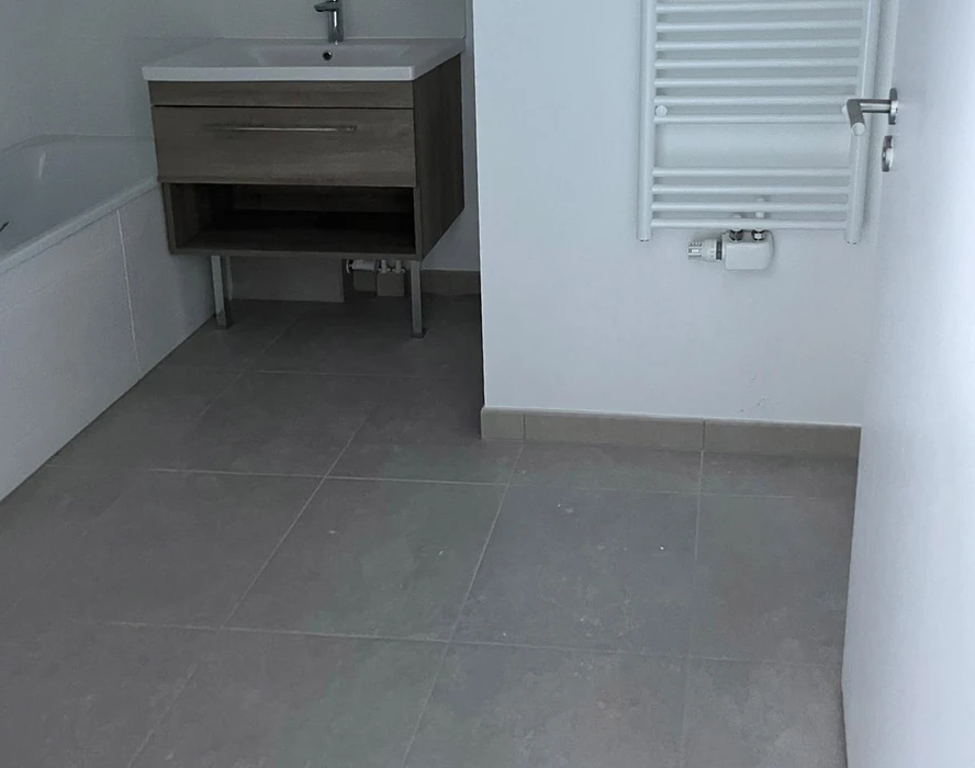 Salle de bain moderne avec carrelage gris anthracite au sol, murs blancs