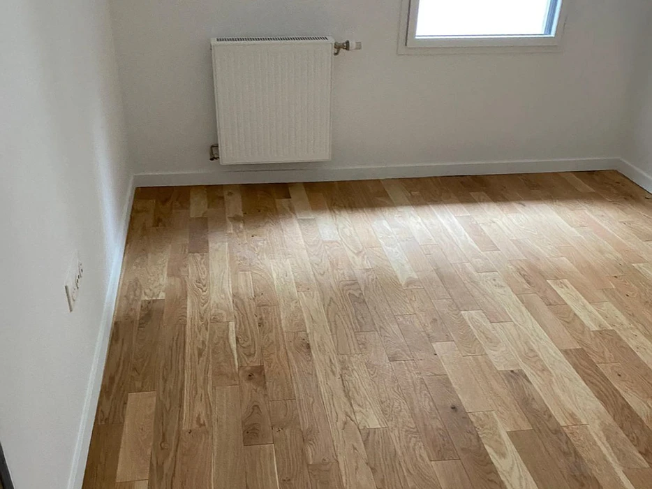 Intérieur de salle de bain en cours de rénovation avec radiateur sèche-serviettes blanc monté au mur, toilettes blanches et niches murales encastrées dans cloison