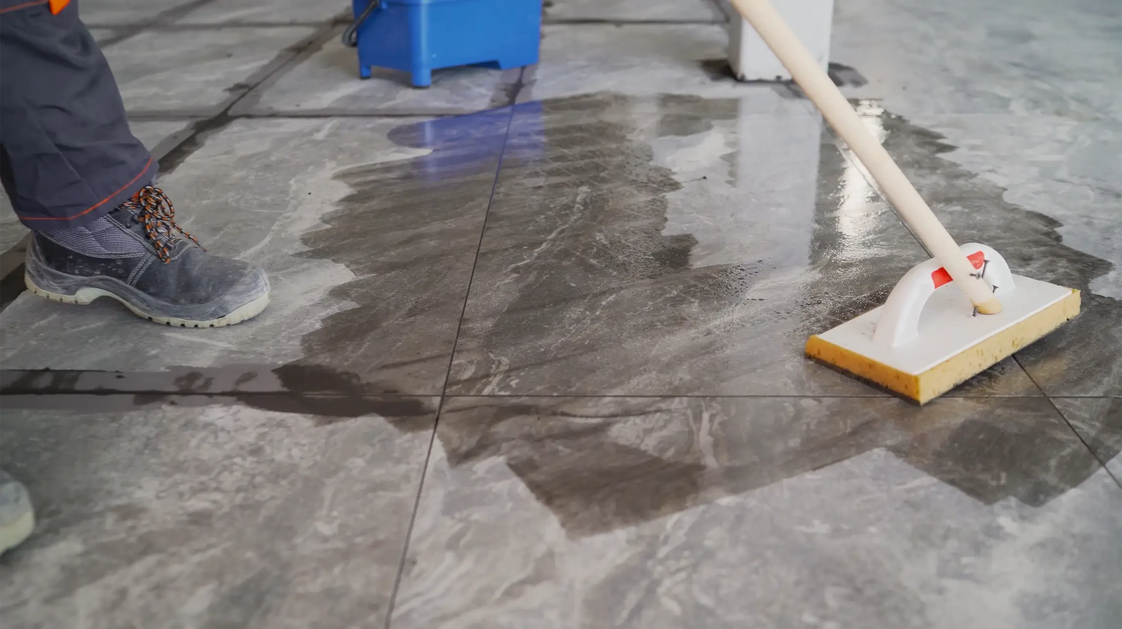 Chantier intérieur, ouvrier en tenue de travail utilisant un aspirateur industriel pour nettoyer le sol béton