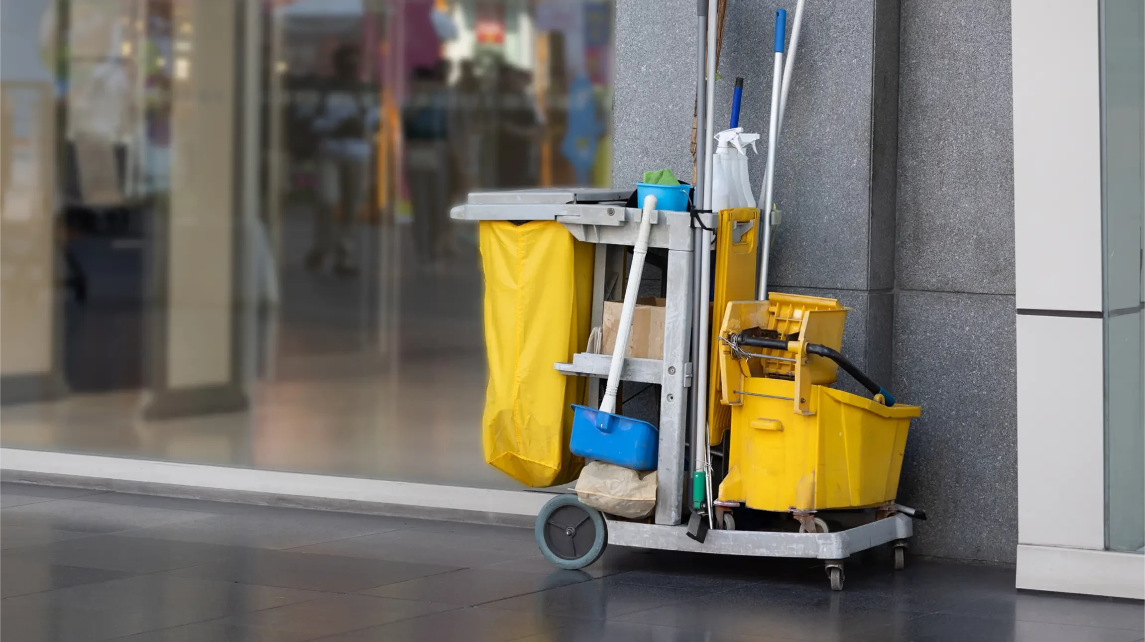 Intérieur commercial moderne avec chariot de nettoyage professionnel jaune stationné près d'un mur blanc