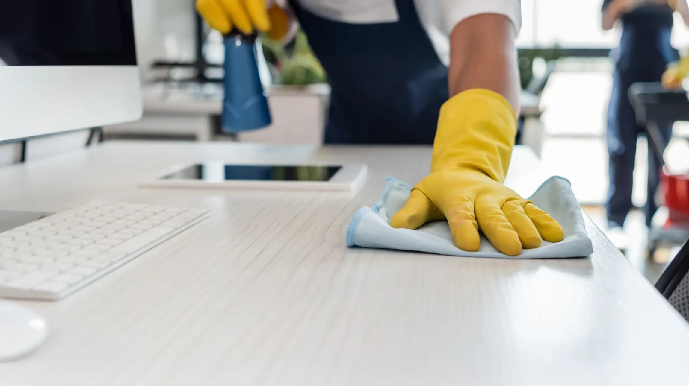 Personne en tenue de travail bleu effectuant le nettoyage professionnel d'un bureau moderne