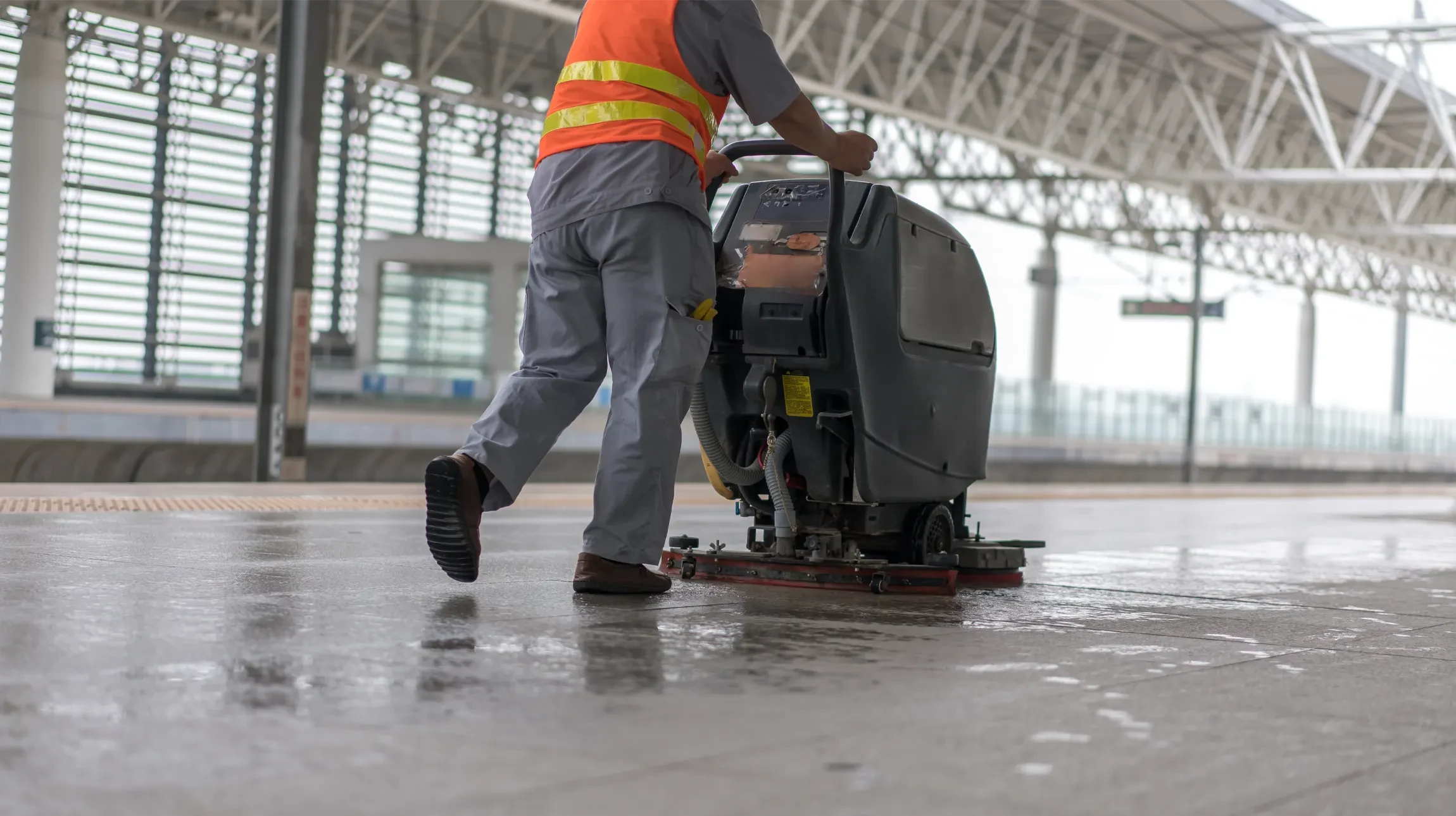 Atelier de maintenance industrielle avec mécanicien en combinaison bleue, bras croisés, tenant clé à molette et gants de protection noirs
